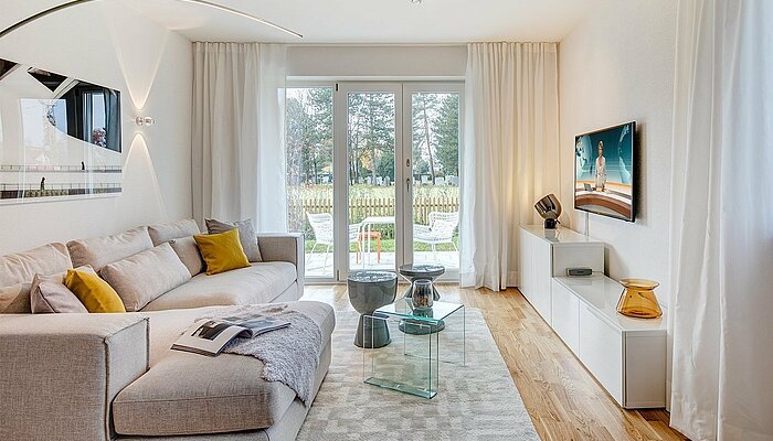 Ein modernes Wohnzimmer mit hellen Möbeln und bodentiefen Fenstern