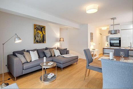 Modern eingerichtetes Wohnzimmer mit offener Küche und gemütlichem Essbereich – stilvoll möblierte Wohnung zur Miete oder zum Kauf bei Mr. Lodge in München.