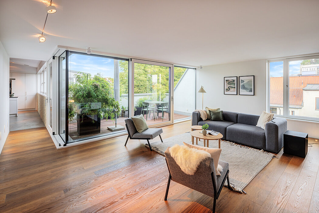 Heller Wohnbereich einer möblierten Wohnung mit Sofa, zwei Sesseln und bodentiefen Fenstern zur Dachterrasse
