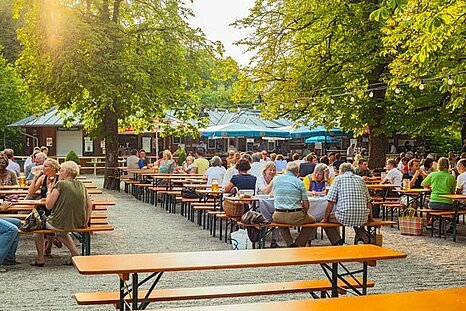 Zu sehen ist ein gut besuchter Biergarten bei sonnigem Wetter