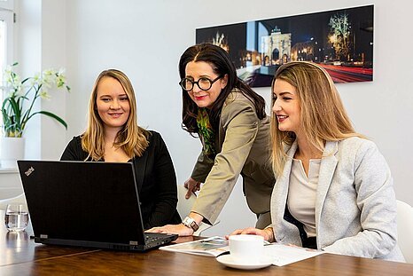 Drei Mr. Lodge Mitarbeiterinnen beraten sich, vor ihnen steht ein Laptop.
