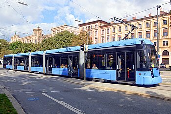 Eine Trambahn des MVV fährt vor einem schönen Altbau.