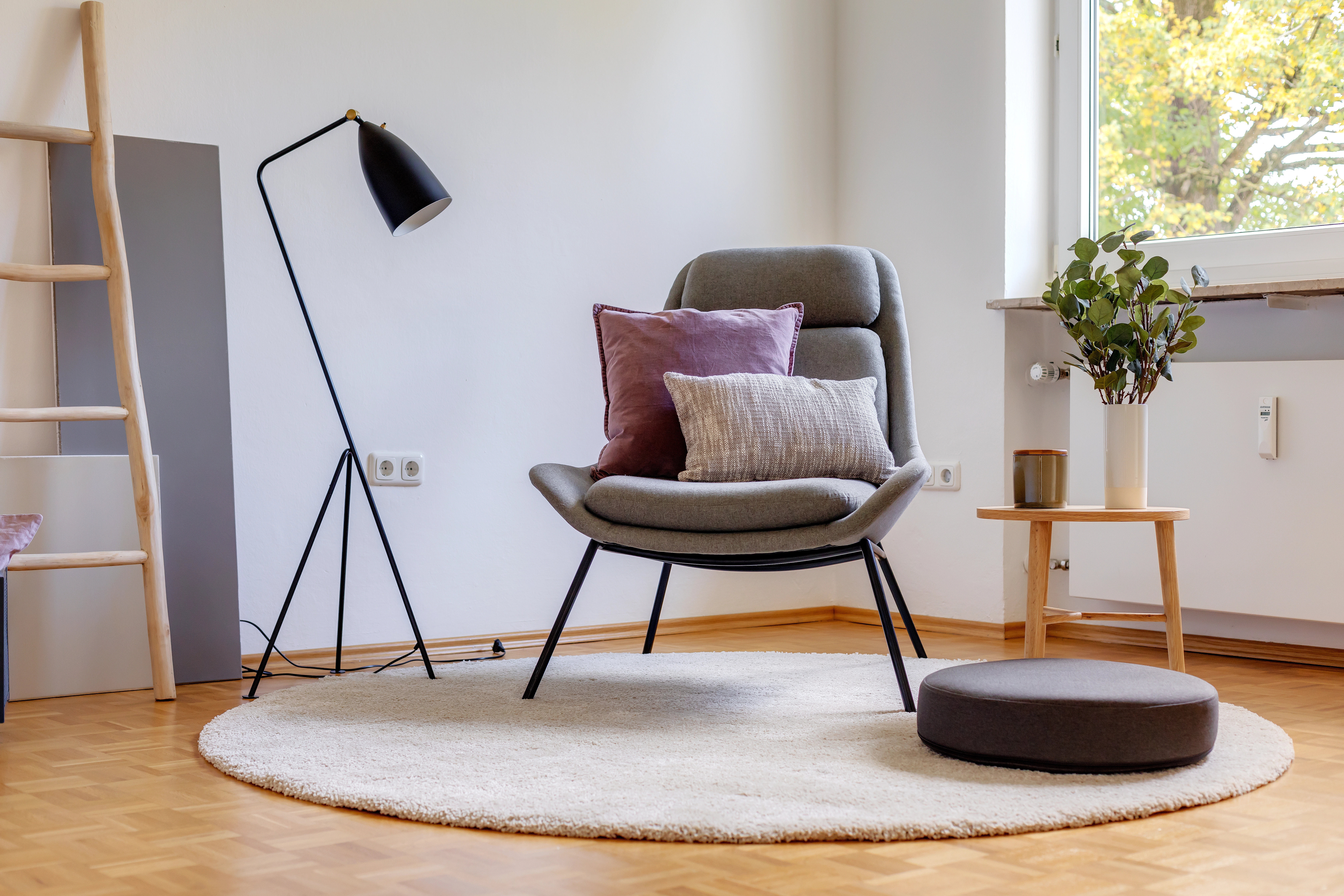 Wohnzimmer nach Home Staging mit Designsessel, Stehlampe und hellem Teppich